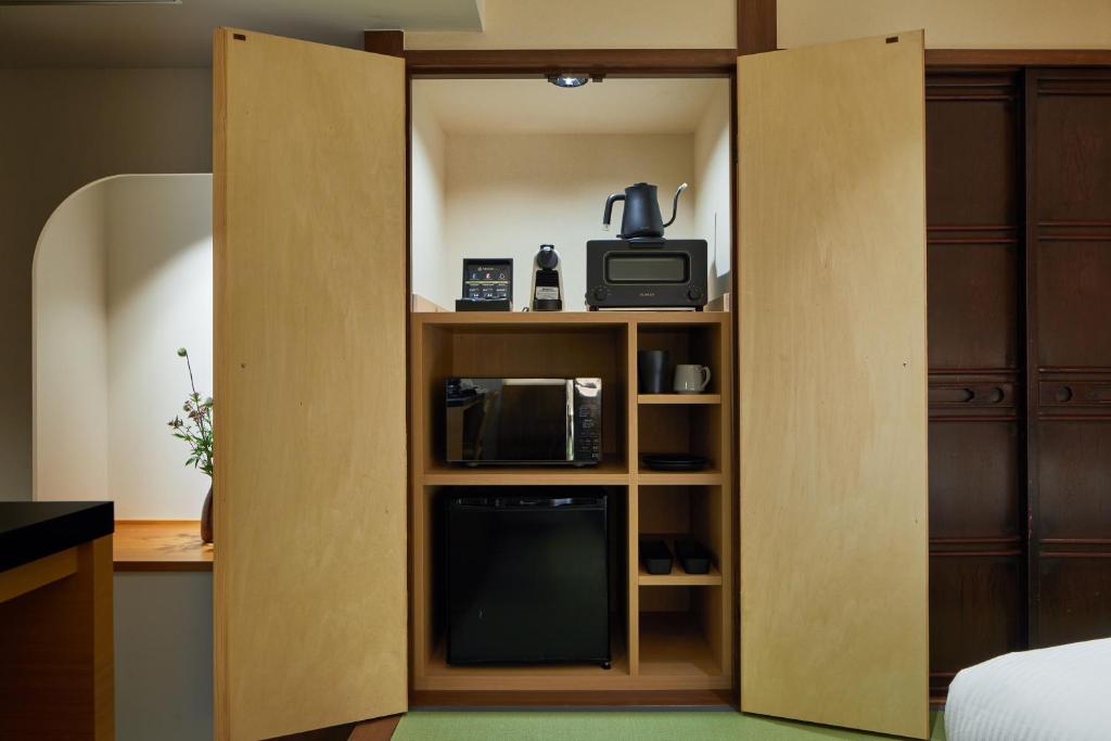 a room with a partition with a tv and a microwave at Enso Machiya in Kyoto