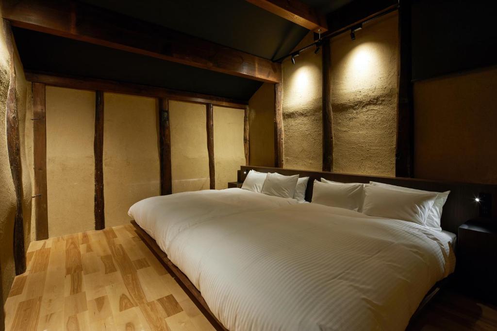 a large bed with white sheets in a room at Enso Machiya in Kyoto