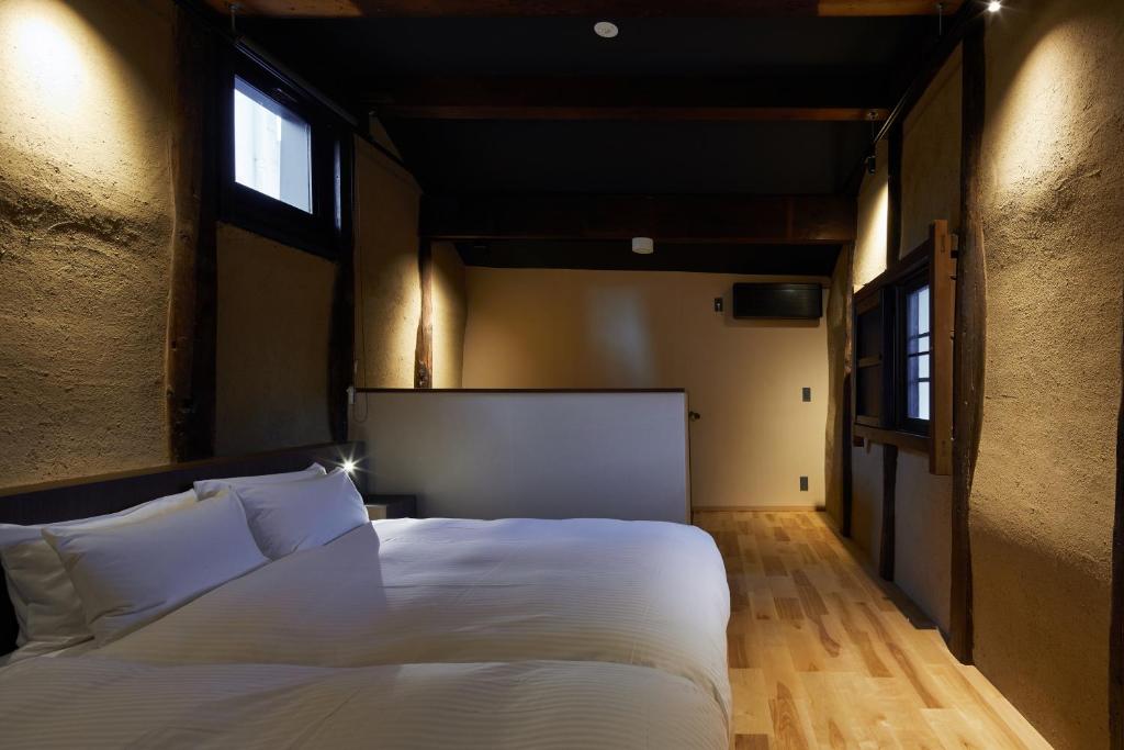 a bedroom with a large white bed and two windows at Enso Machiya in Kyoto