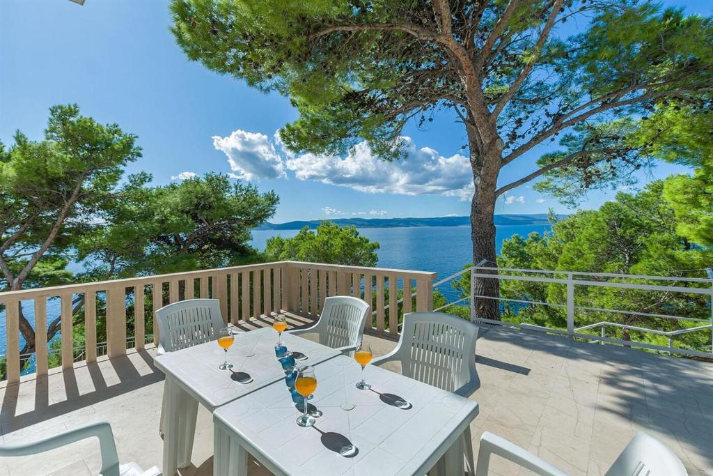 un tavolo bianco e sedie su una terrazza con vista sull'acqua di A Minute to the Sea Brela a Brela