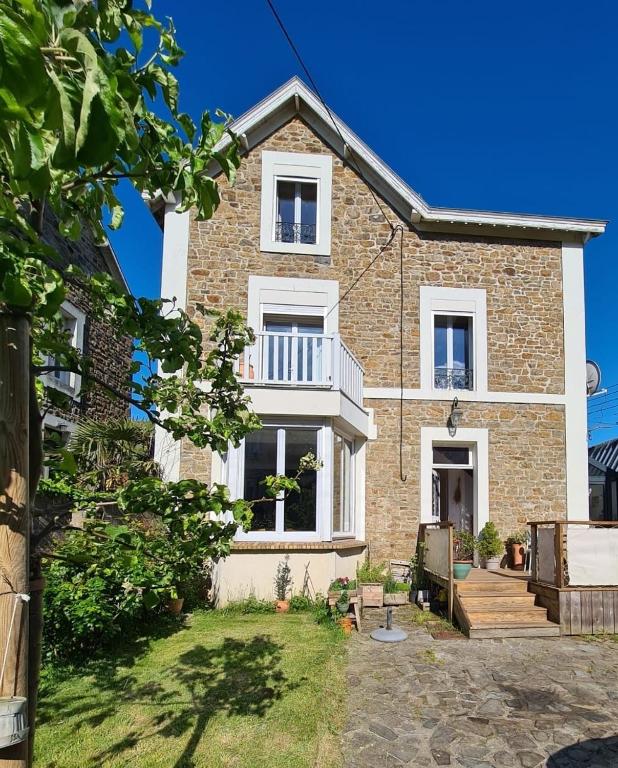 une grande maison en briques avec des fenêtres blanches et une cour dans l'établissement La Servannaise - A 600 de la plage, à Saint-Malo