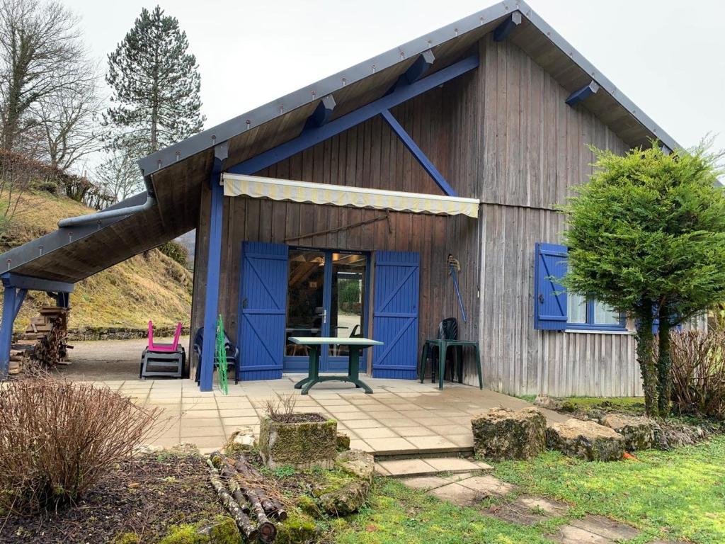 a blue building with a patio in front of it at Chalet Les Ammonites 2 chambres en Franche Comte au calme dans la nature in Nans-sous-Sainte-Anne