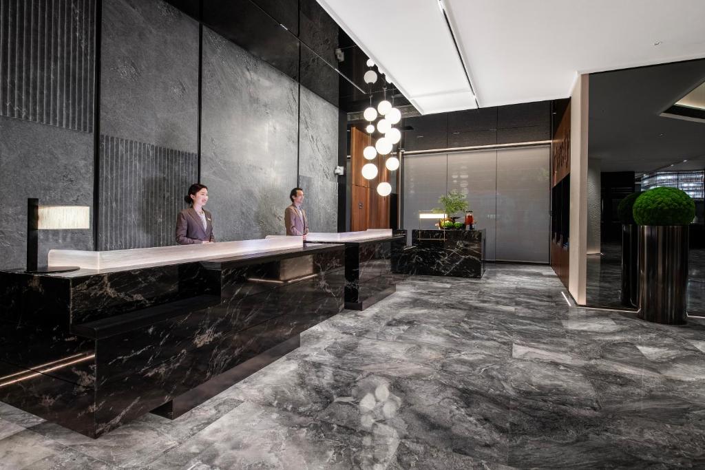 two people standing at a long desk in a lobby at Intercity Hotel Shanghai City Center - Free Mini Bar in Shanghai