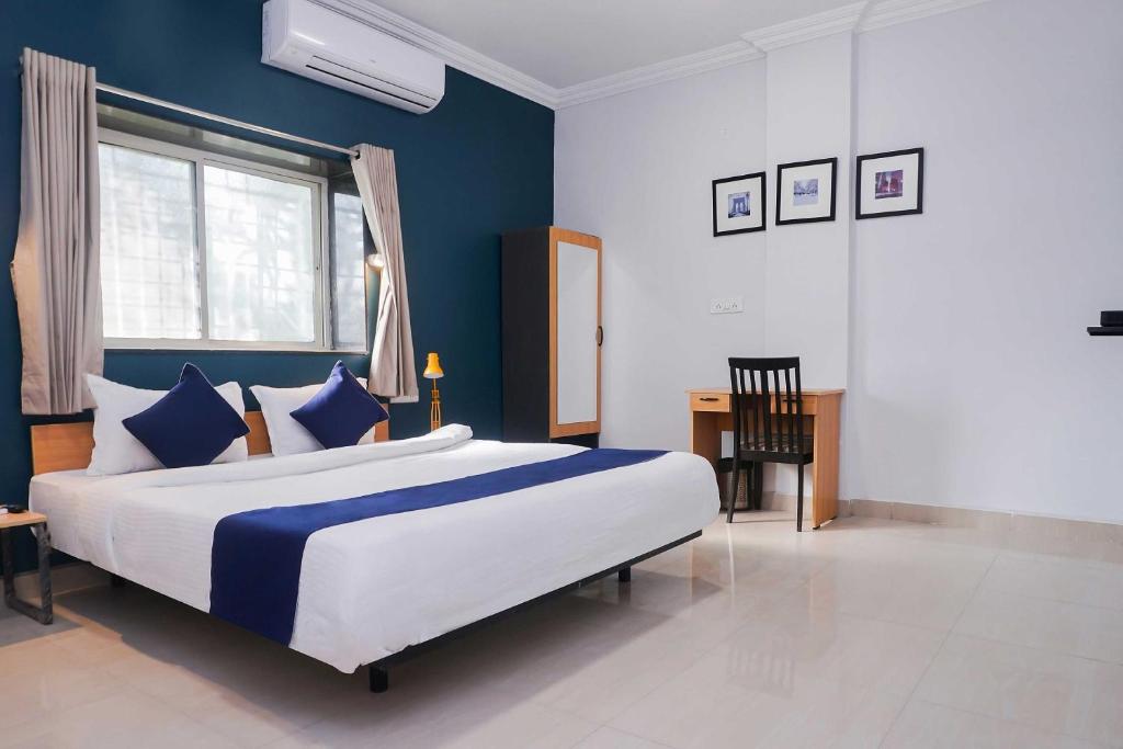 a bedroom with a bed with blue walls and a desk at OYO 77138 Shree Apartments in Khadki