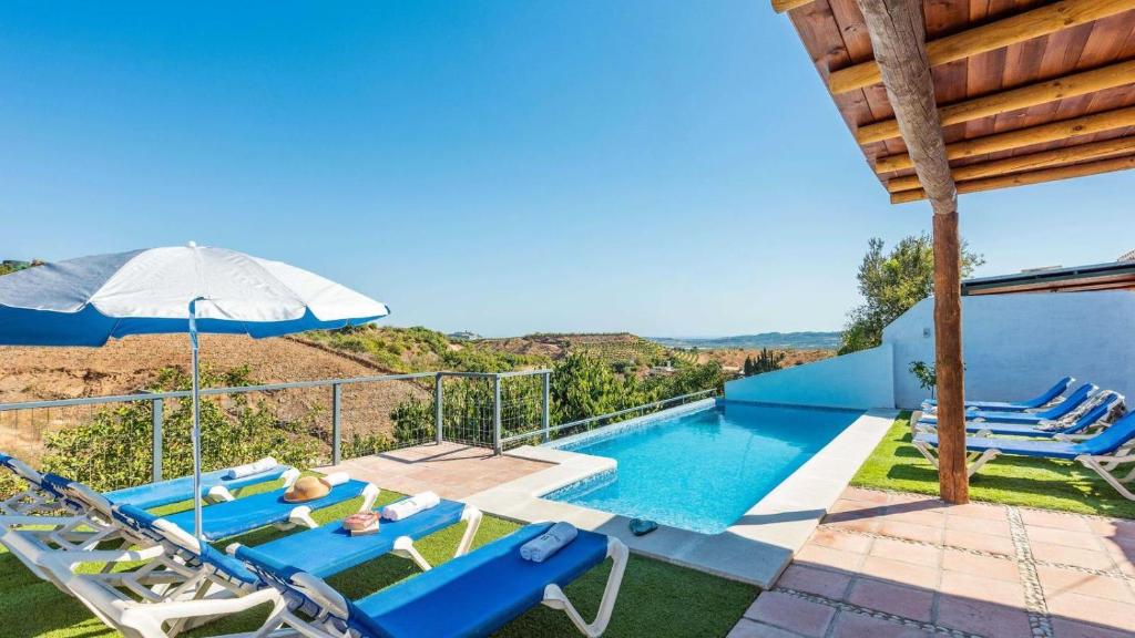 a villa with a swimming pool with chairs and an umbrella at Casa La Estrella Azul Vélez-Málaga by Ruralidays in Vélez-Málaga
