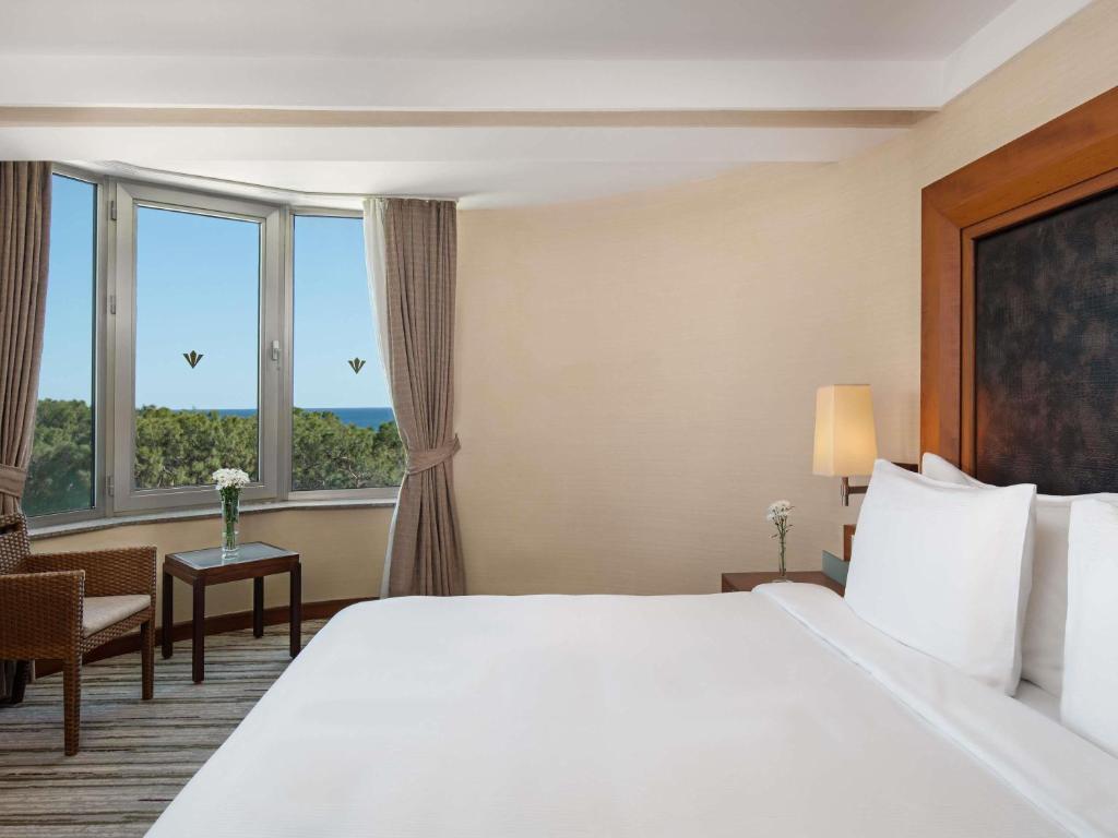 a hotel room with a large bed and windows at Rixos Sungate - The Land of Legends Access in Beldibi