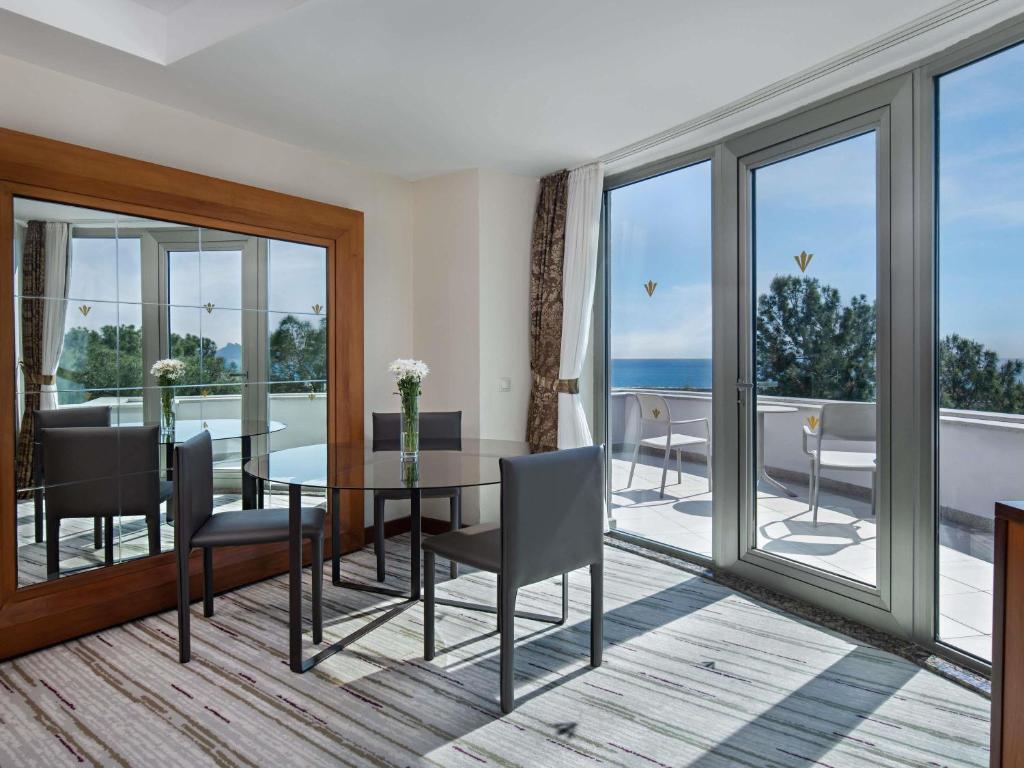 a living room with a table and chairs and a balcony at Rixos Sungate - The Land of Legends Access in Beldibi