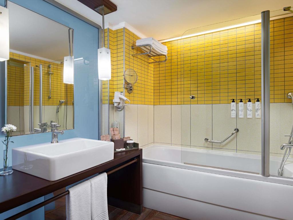a bathroom with a sink and a tub and yellow tiles at Rixos Sungate - The Land of Legends Access in Beldibi