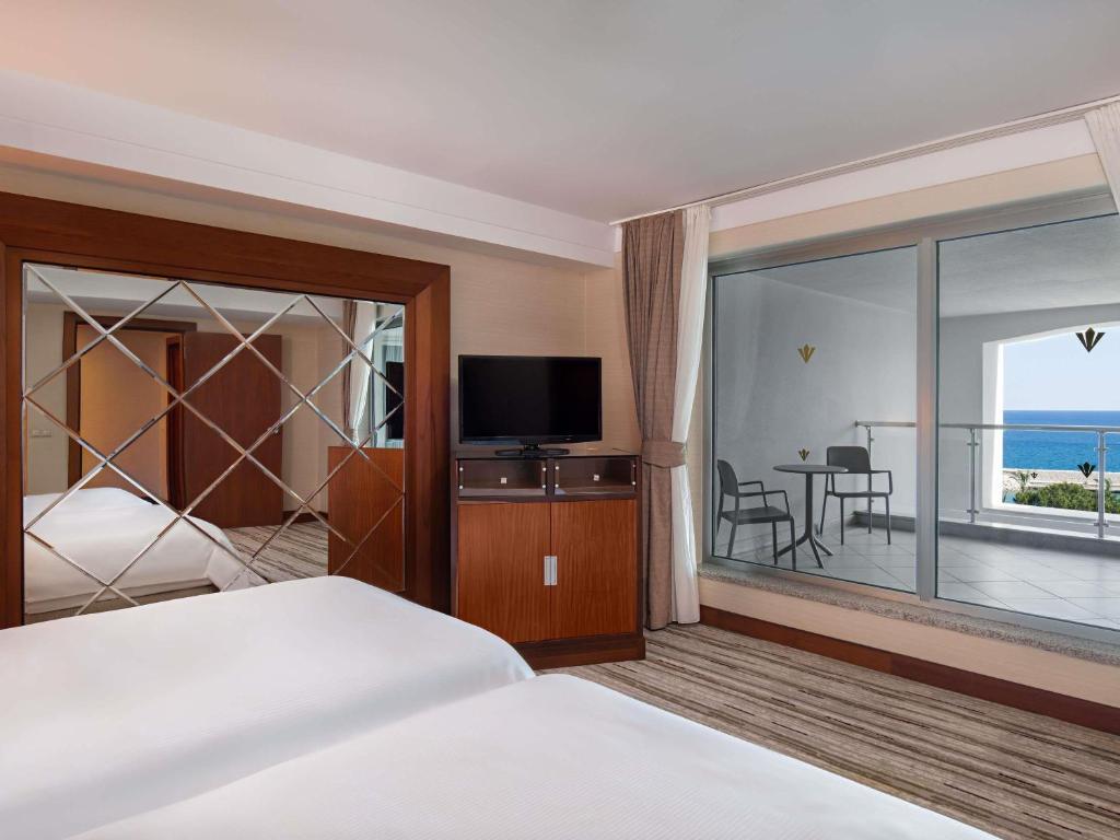 a hotel room with a bed and a view of the ocean at Rixos Sungate - The Land of Legends Access in Beldibi