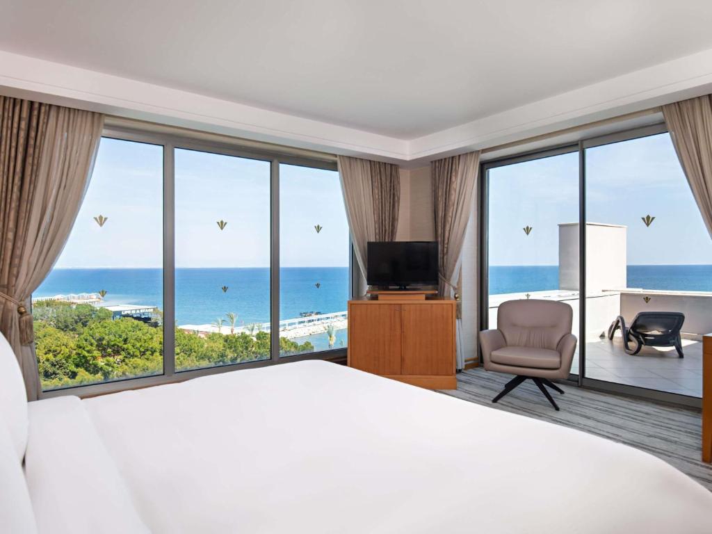 a hotel room with a bed and a view of the ocean at Rixos Sungate - The Land of Legends Access in Beldibi