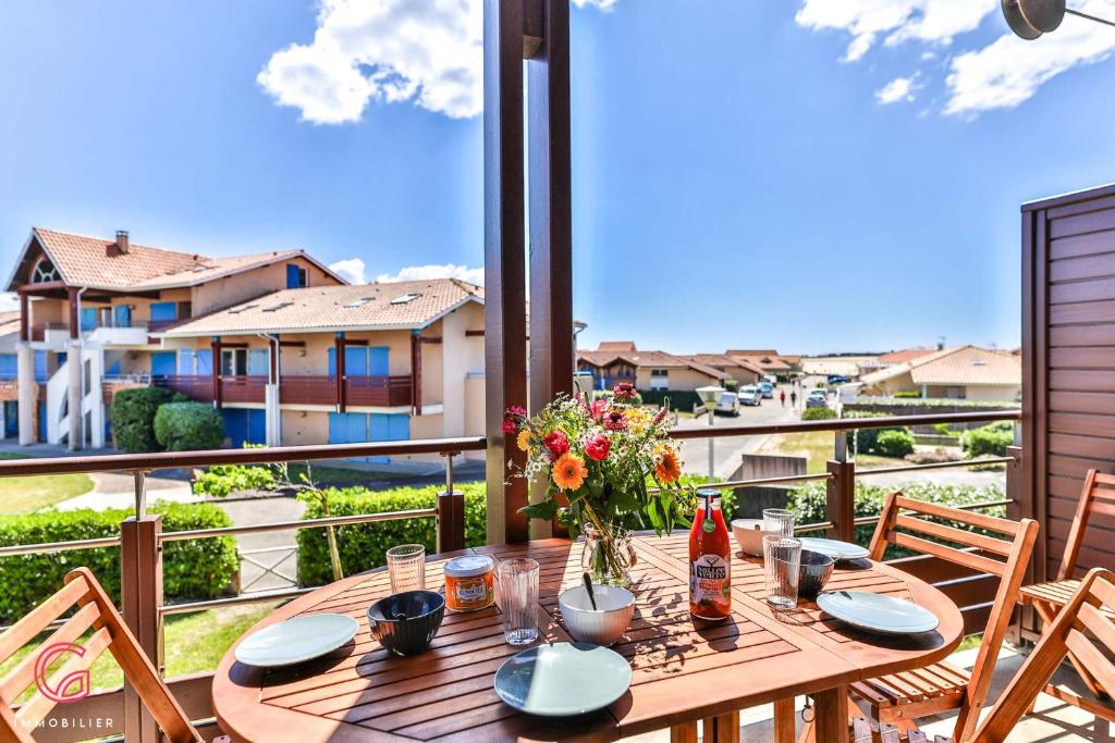 - une table en bois avec des fleurs sur le balcon dans l'établissement Duplex cosy à 200m de la plage, à Biscarrosse