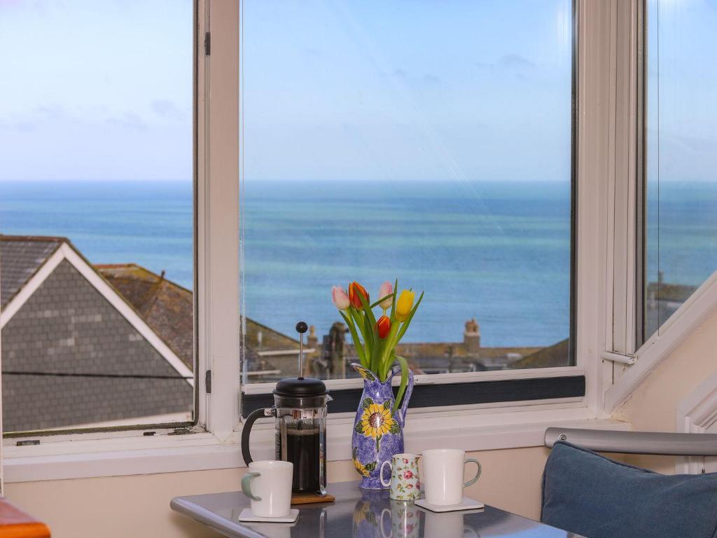 a vase of flowers on a table in front of a window at Breakers Point in St Ives