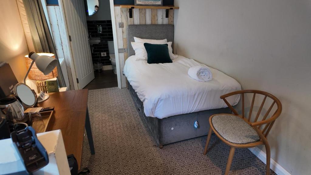 a small bedroom with a bed and a desk at Downs Hotel in Stanmer