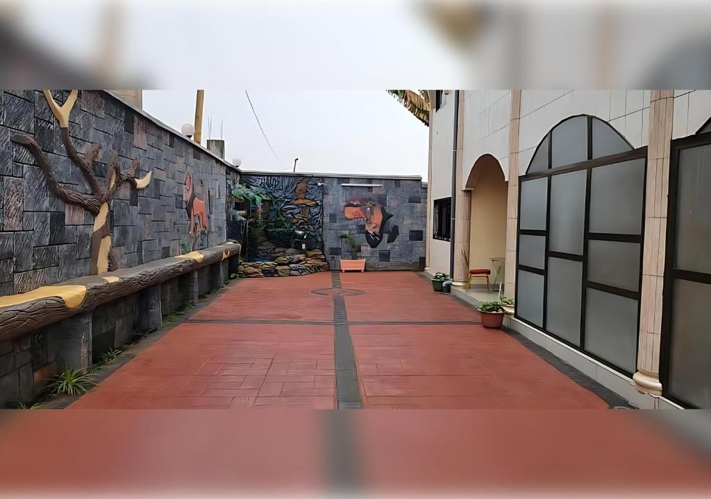 a brick walkway with a mural on the side of a building at NEFAR PALACE HOTEL Plc in Bafoussam