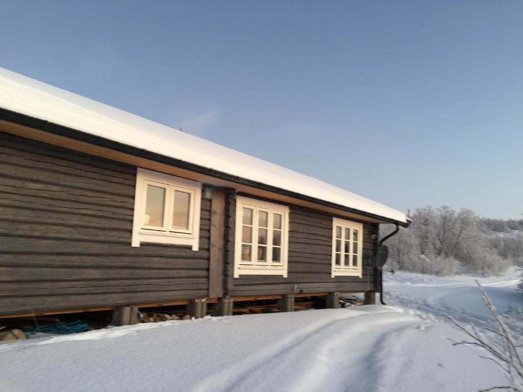 a wooden house with windows on a snow covered road at Cottage Lavkavann Finnmarksvidda in Skoganvarre