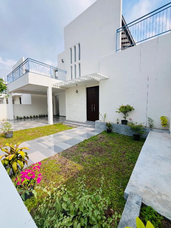 a white house with a courtyard with pink flowers at Celestial Negombo Villa 41 in Negombo