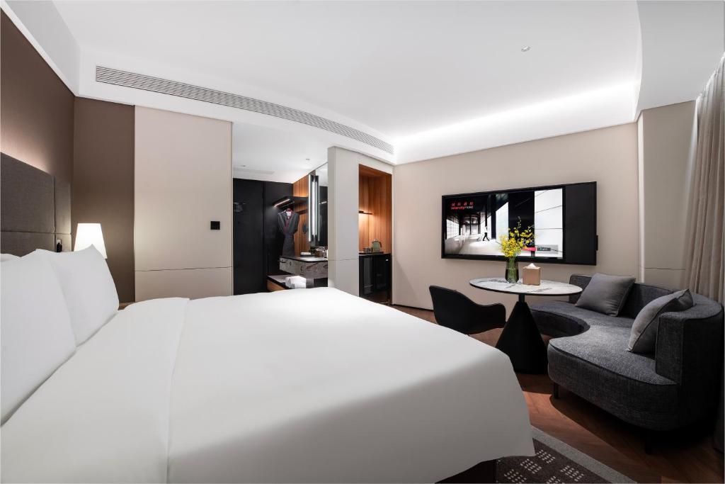 a bedroom with a large white bed and a living room at Intercity Hotel Shanghai City Center - Free Mini Bar in Shanghai