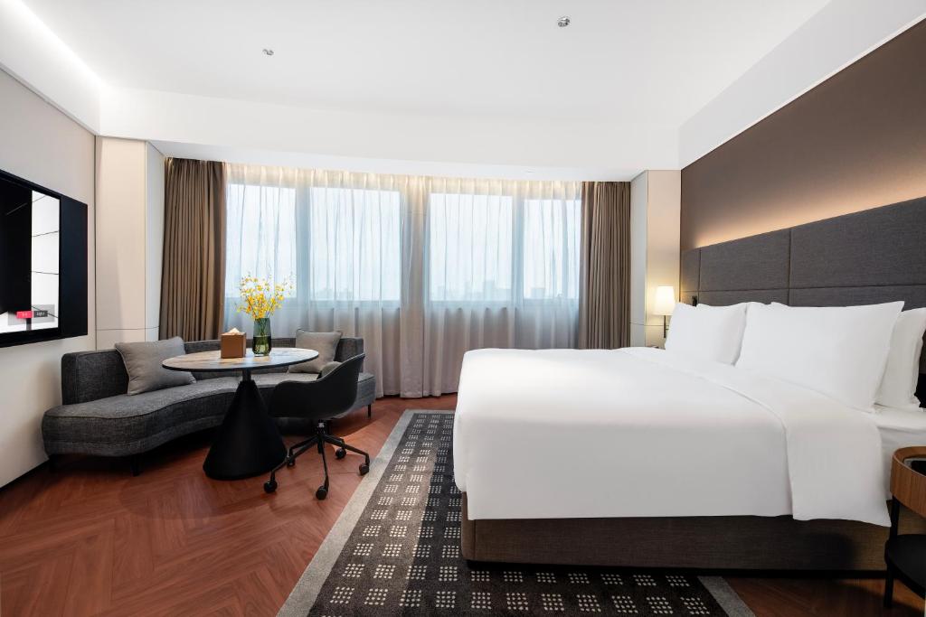 a hotel room with a large white bed and a couch at Intercity Hotel Shanghai City Center - Free Mini Bar in Shanghai