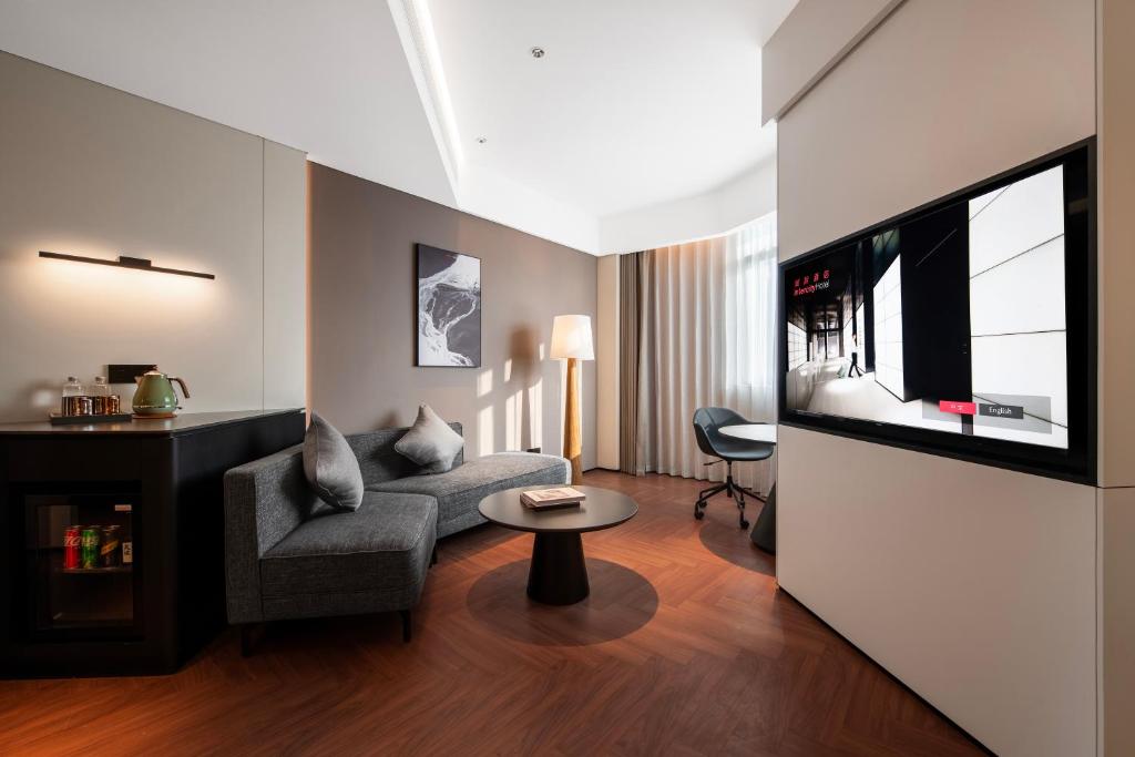 a living room with a couch and a tv at Intercity Hotel Shanghai City Center - Free Mini Bar in Shanghai