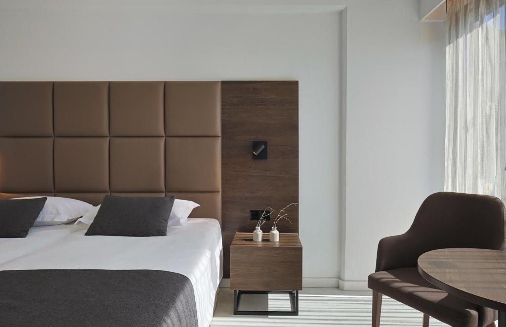 a bedroom with a bed and a chair and a table at Odysseia Hotel Kapetanios in Limassol