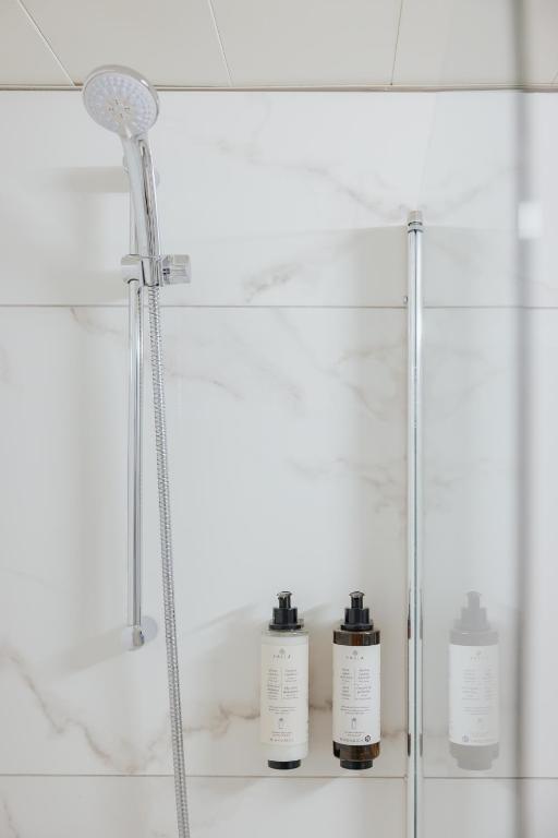 a shower in a bathroom with three bottles on a shelf at Odysseia Hotel Kapetanios in Limassol