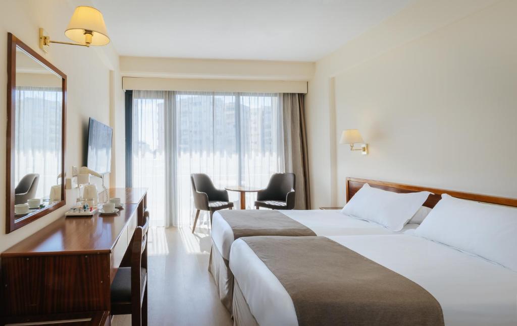 a hotel room with two beds and a table at Odysseia Hotel Kapetanios in Limassol