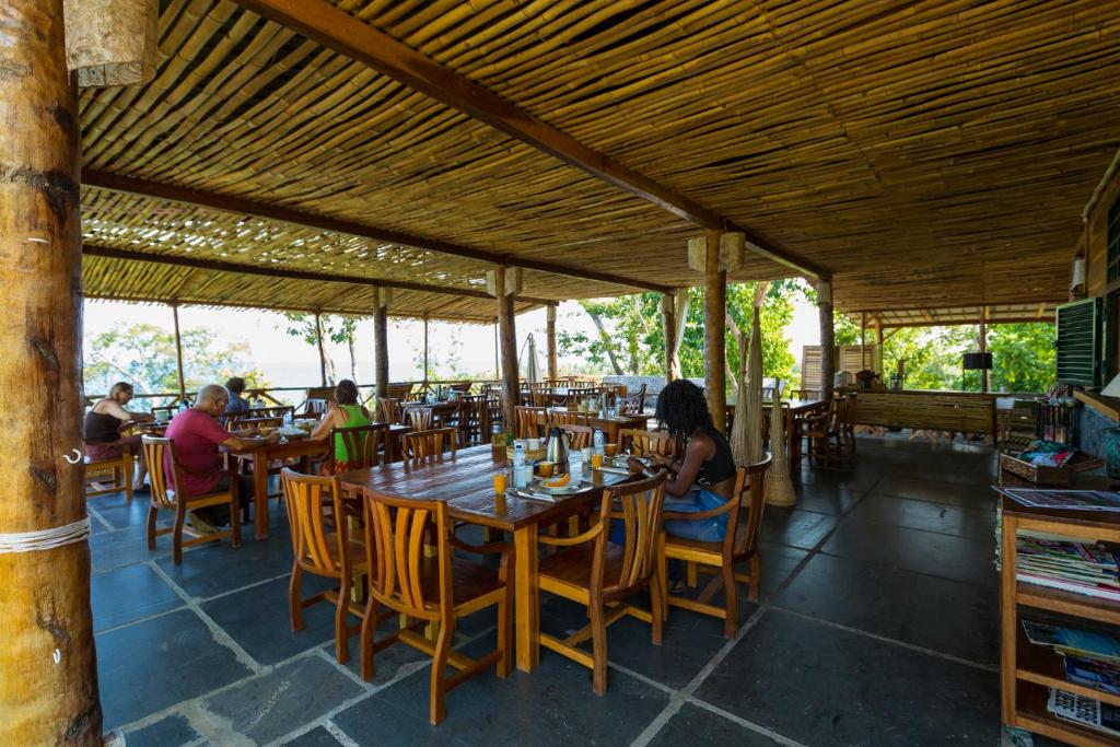 uma sala de jantar com uma mesa de madeira e cadeiras em Mucumbli em Ponta Figo