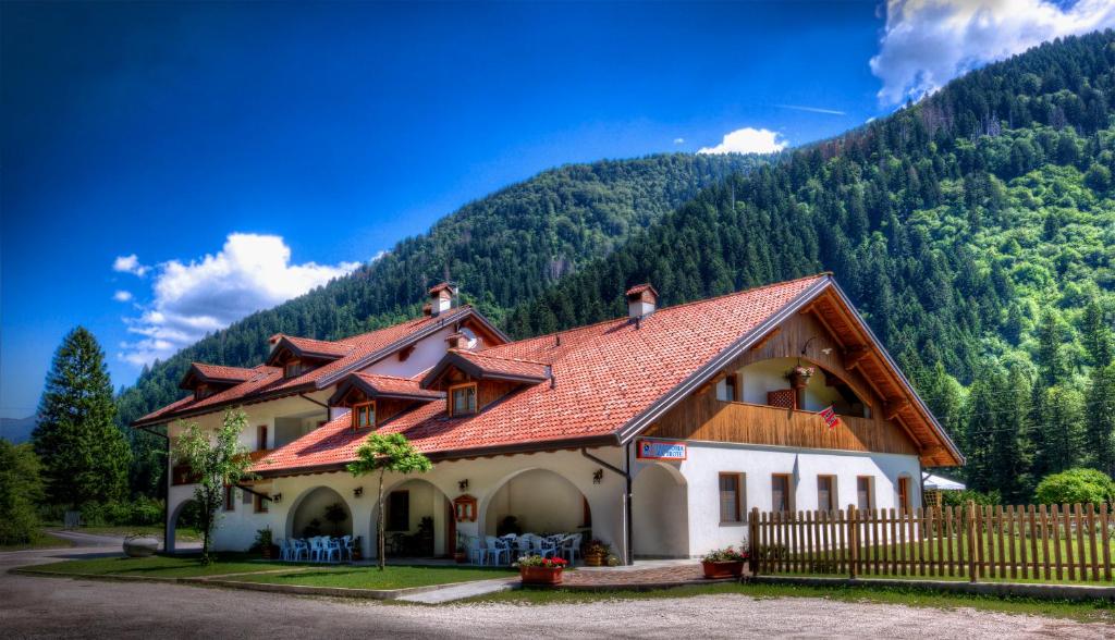 a house with a red roof in front of a mountain at Affittacamere Alle Trote in Sùtrio