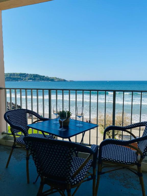 une table et des chaises sur un balcon avec la plage dans l'établissement Nahia, à Hendaye