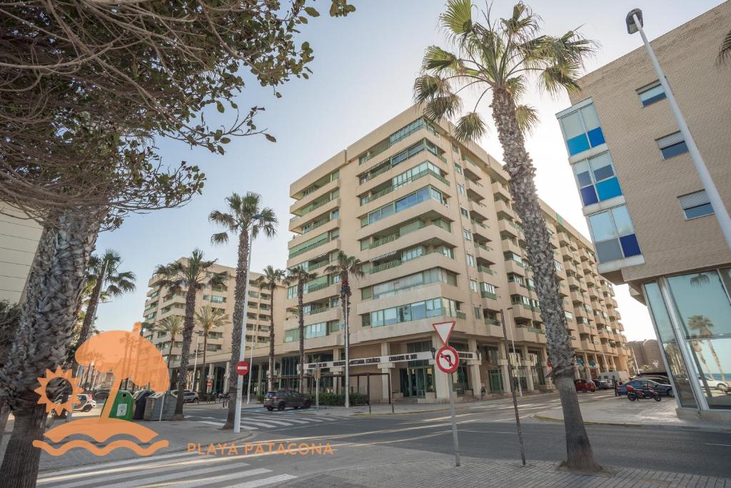 een groot gebouw aan een stadsstraat met palmbomen bij Front Sun Beach Apartment in Valencia