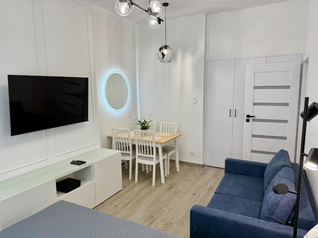 ein Wohnzimmer mit einem blauen Sofa und einem Fernseher in der Unterkunft City & Sea - Apartamenty i Mieszkania in Gdynia