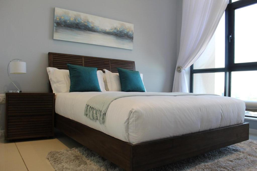a bedroom with a large bed with blue pillows at iTowers Luxury Apartment in Gaborone