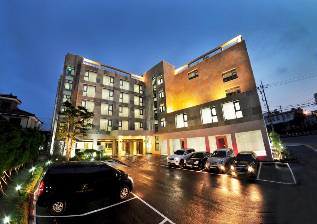 a parking lot with cars parked in front of a building at Black Sands Hotel Jeju in Jeju