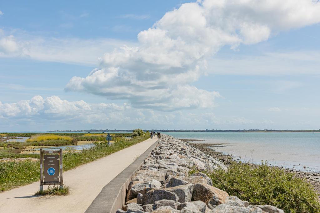 a walkway along the shore of a body of water at Maison vue mer et marais salants in Loix