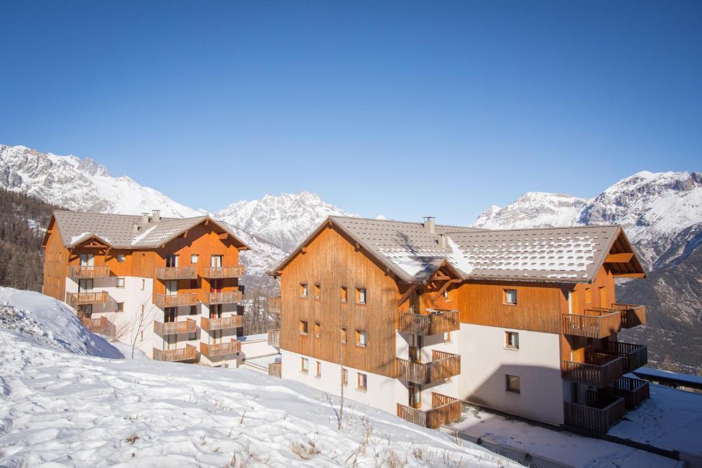 a building in the snow with mountains in the background at Les Gentianes by Actisource in Puy-Saint-Vincent