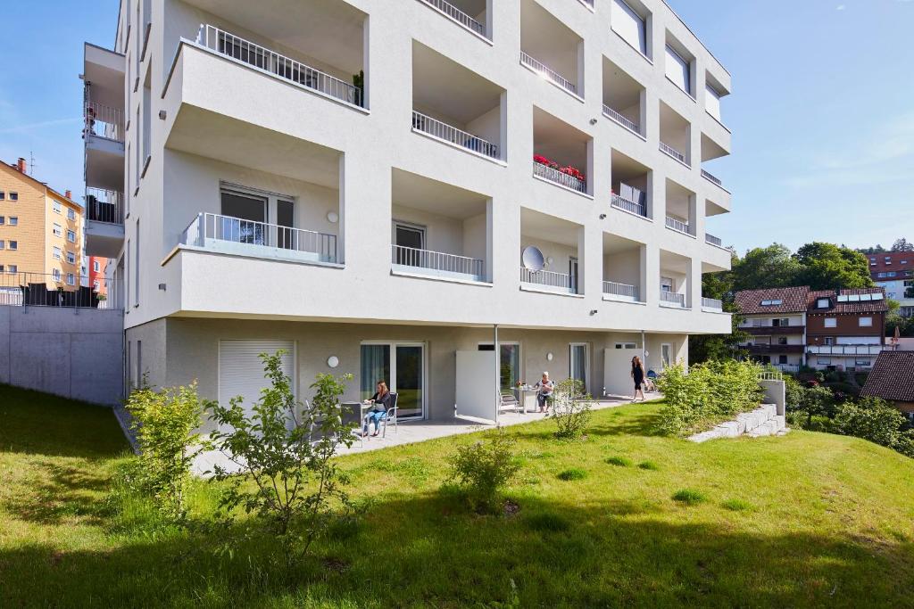 un immeuble d'appartements blanc avec des personnes assises dans une cour dans l'établissement Auszeit Urlaub mit Pflege, à Sankt Georgen im Schwarzwald