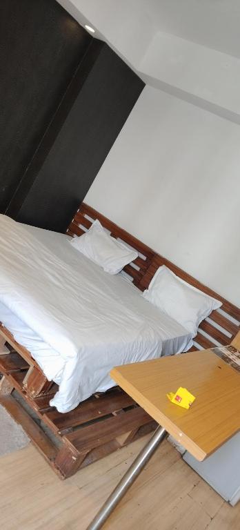 a bed with white sheets and a wooden table at DLF MyPad in Lucknow