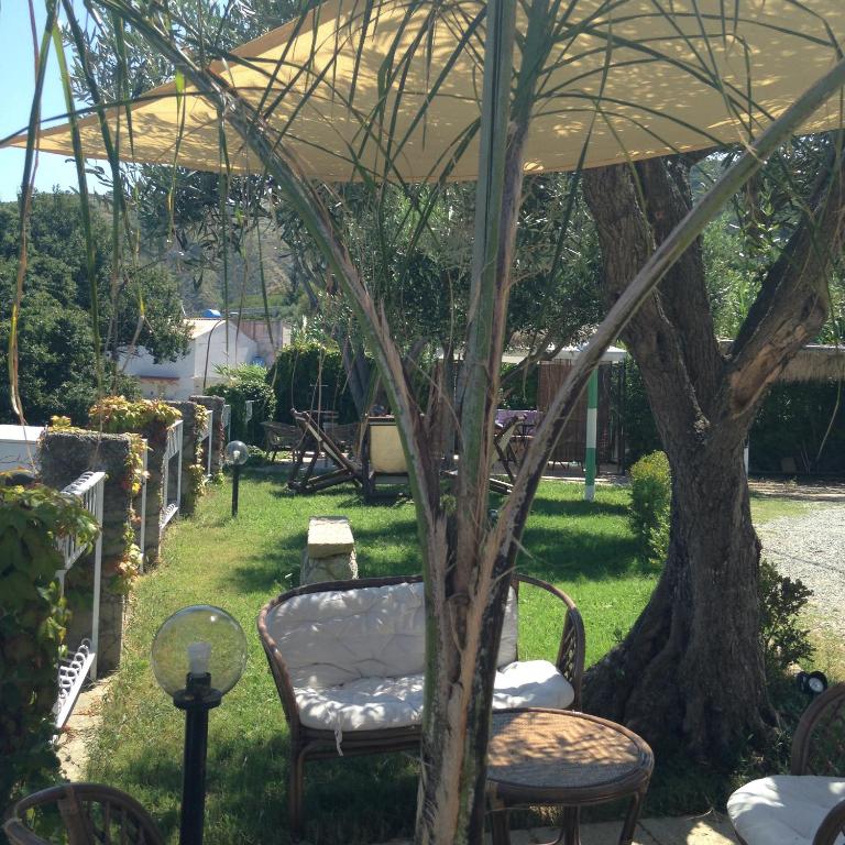 a table and chairs under an umbrella in a yard at Residenza Casale San Francesco free parking in Tropea