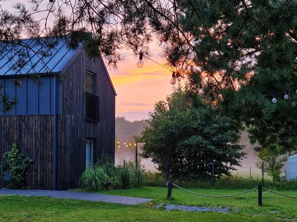 a barn in a field with a sunset in the background at Domki Czarny Bocian in Białogóra