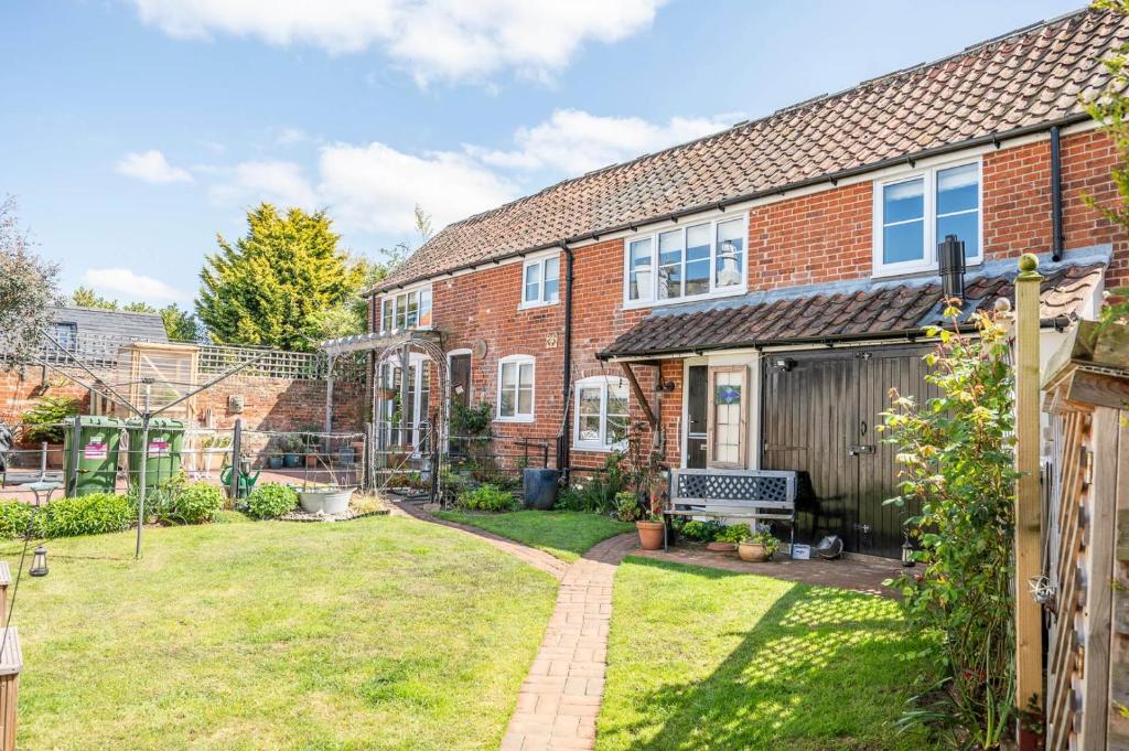 een bakstenen huis met een tuin ervoor bij Stable Cottage, Friston in Friston