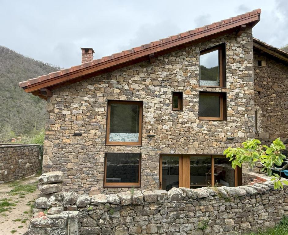 a stone house with a stone wall at La era de Somaniezo in Luriezo
