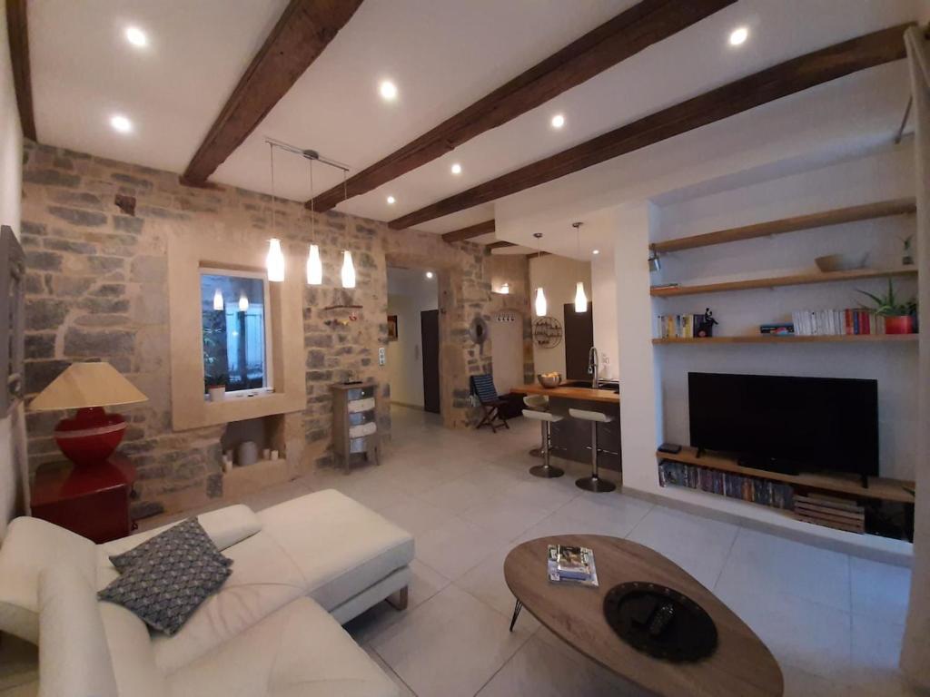 un soggiorno con un divano bianco e un muro di pietra di Appartement grand confort au cœur de Millau a Millau