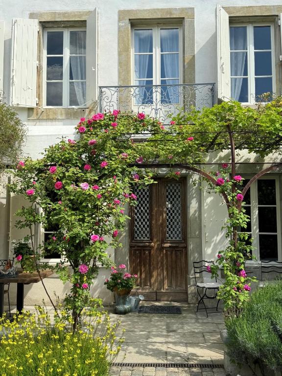 une arche avec des fleurs roses devant une maison dans l'établissement Le Patio Des Senteurs, à Verzeille