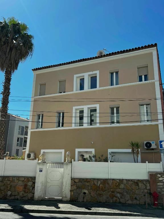 un bâtiment avec une clôture et un palmier dans l'établissement Residence Enzo Paradise, à La Seyne-sur-Mer