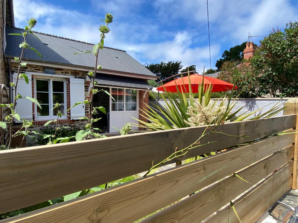 une clôture devant une maison avec un parapluie rouge dans l'établissement Grains de Sable, à Barneville-Carteret