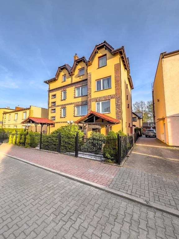 a yellow building on a street with a fence at Willa Koron a Mielno in Mielno