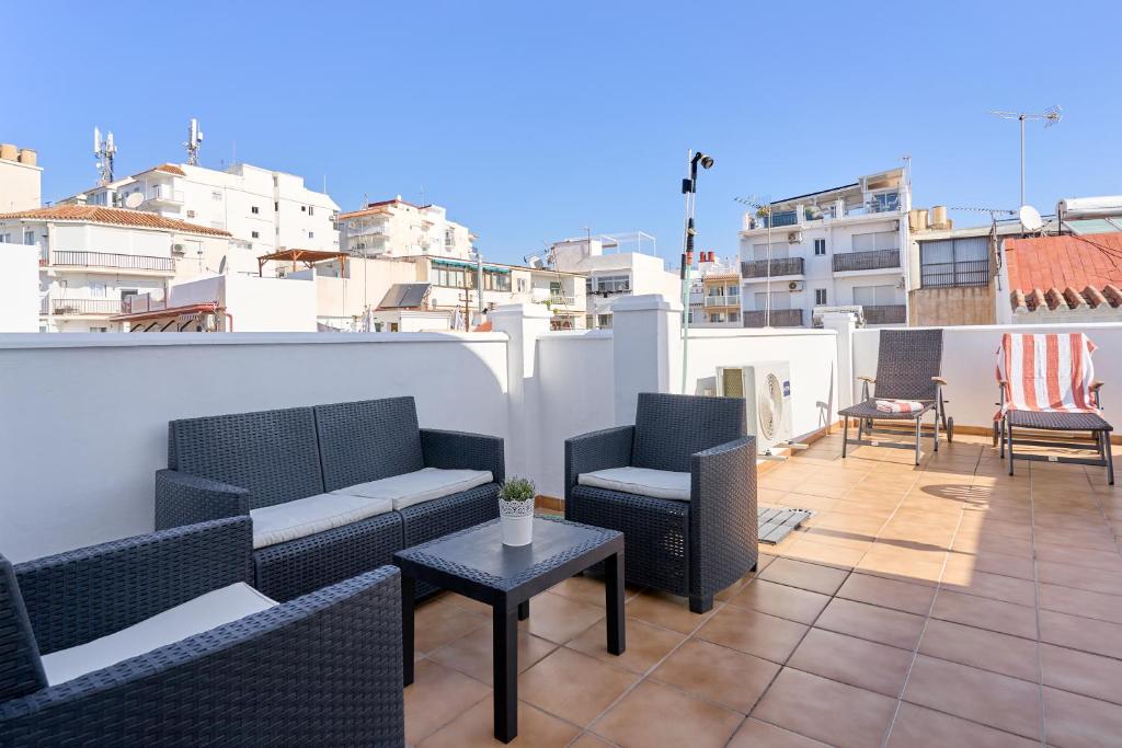 a patio with chairs and tables on a roof at Apartamento B y G Nerja in Nerja