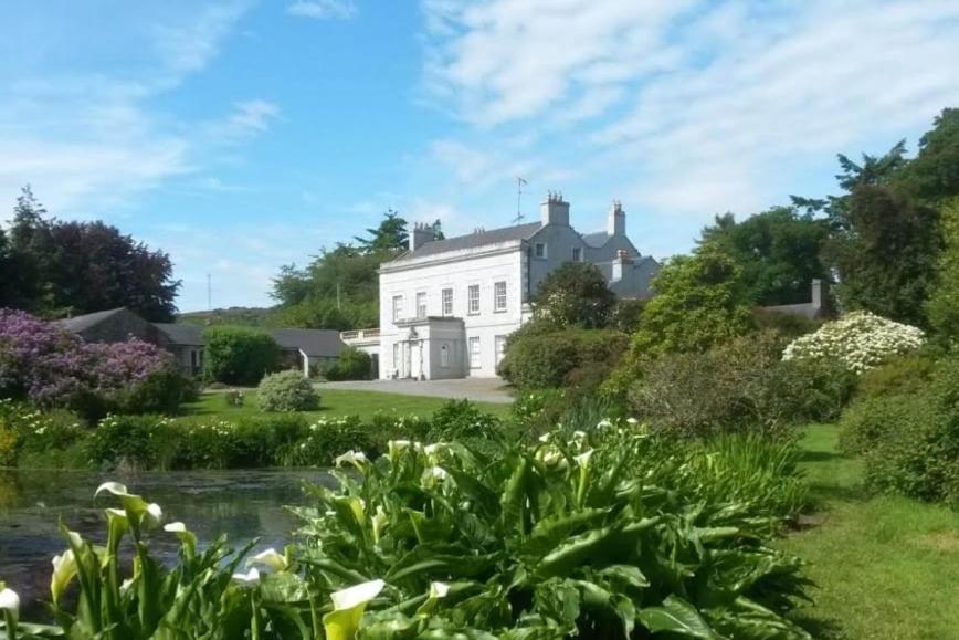a white house with a pond in front of it at Kilmartin House - Georgian House on Private Estate and Farm in Greystones