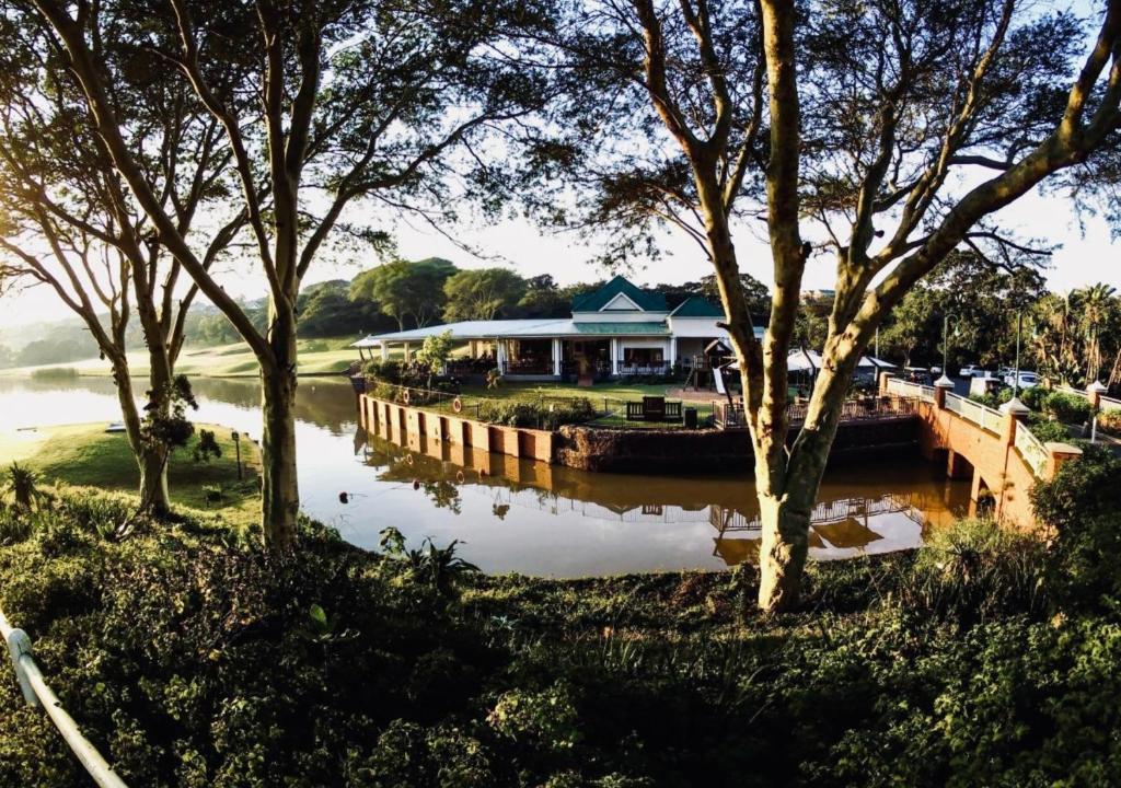 a house next to a river with trees at Cosy Urban Apartment in Durban