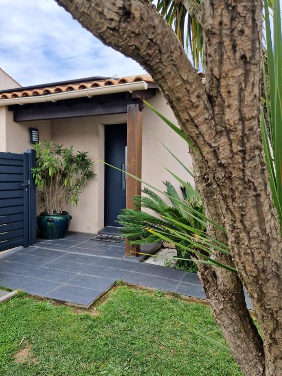 une maison avec une porte bleue et un palmier dans l'établissement L'oiseau du paradis, à La Celle-sous-Gouzon